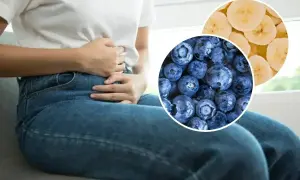 Osoba z bólem brzucha trzyma się za żołądek. Obok zdjęcia jagód i plasterków banana, które mogą pomóc na biegunkę.