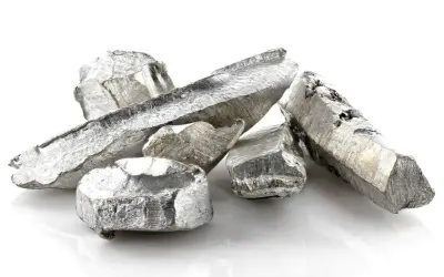 Kawałki metalicznego kadmu o srebrzystym połysku, ułożone na białym tle.