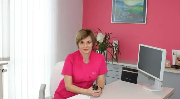 Lekarka w gabinecie dermatologii estetycznej, siedzi przy biurku.