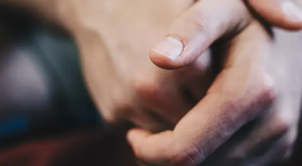 Zbliżenie na dłonie, palec wskazujący z czystym paznokciem, jakby szukał czegoś w piasku z **krzem**u.