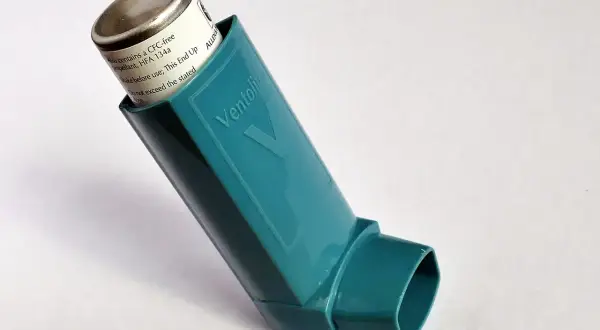 Inhalator Ventolin w kolorze turkusowym na białym tle.