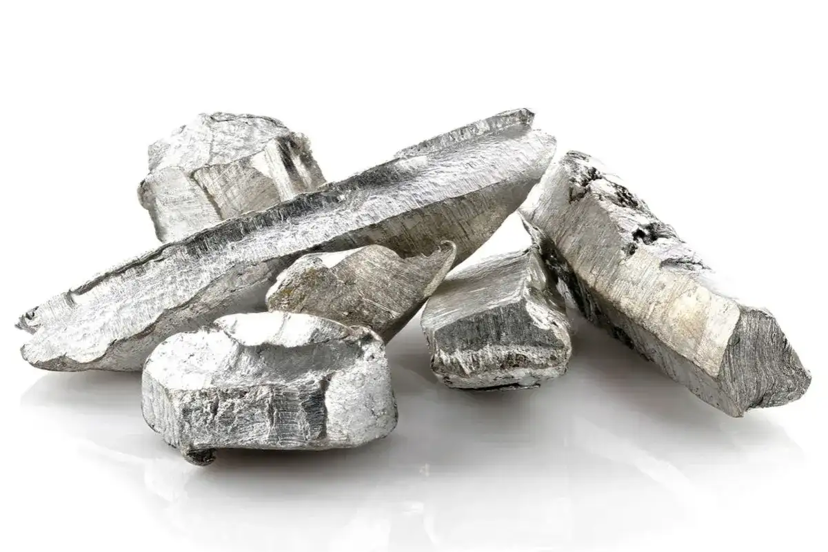 Kawałki metalicznego kadmu o srebrzystym połysku, ułożone na białym tle.