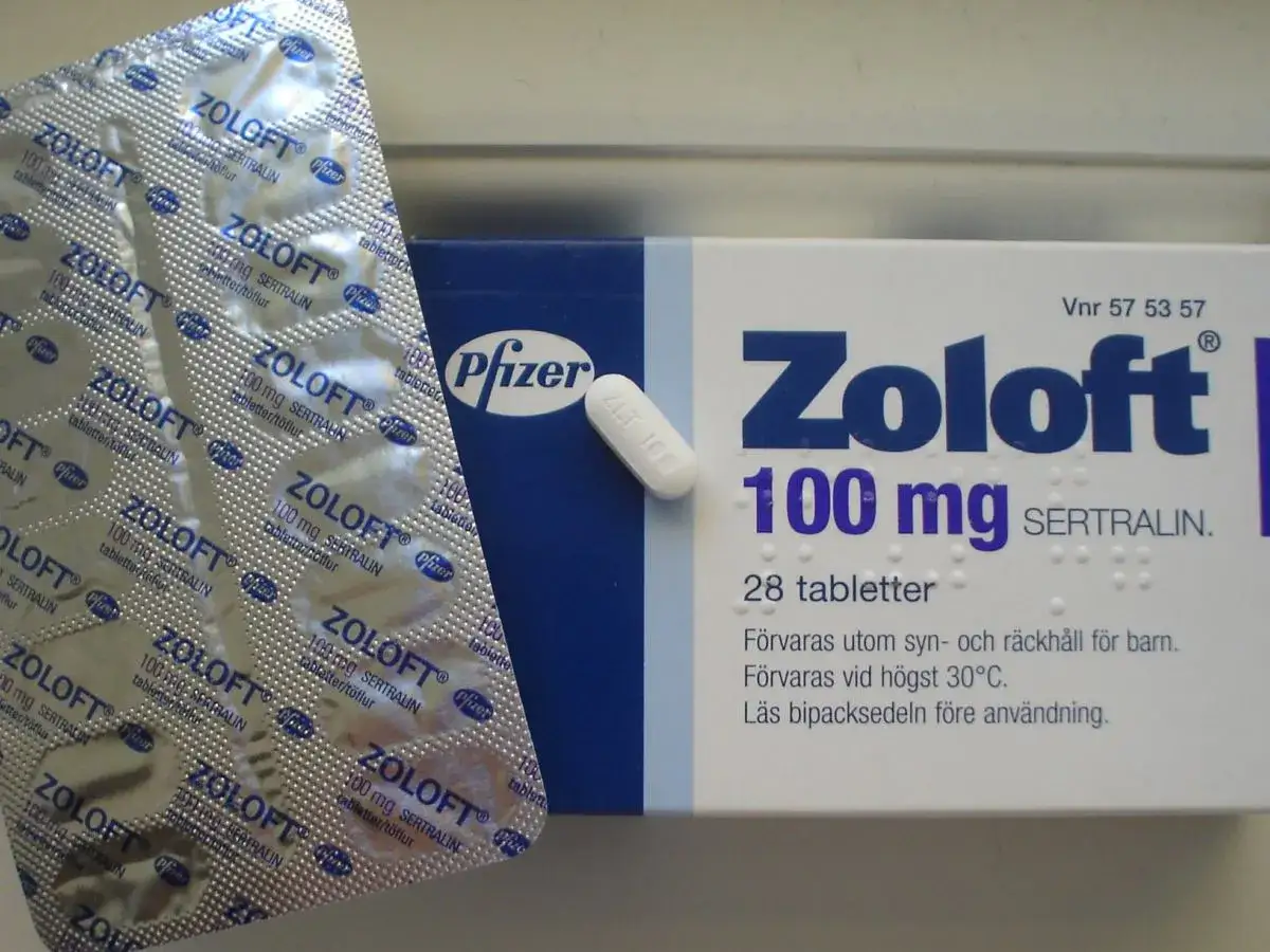 Opakowanie leku Zoloft 100 mg z sertraliną, obok blistra tabletek.