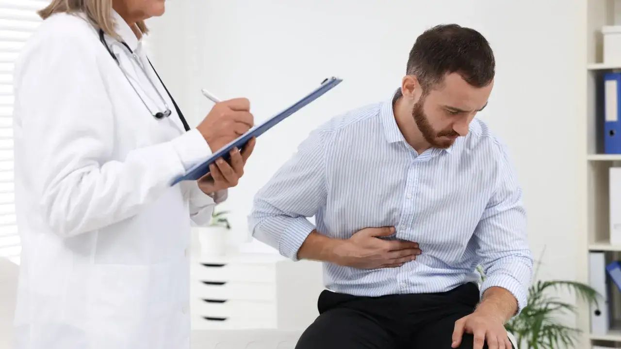 Mężczyzna skarży się na ból brzucha, lekarz notuje objawy. Może to być helicobacter pylori objawy.