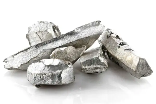 Kawałki metalicznego kadmu o srebrzystym połysku, ułożone na białym tle.